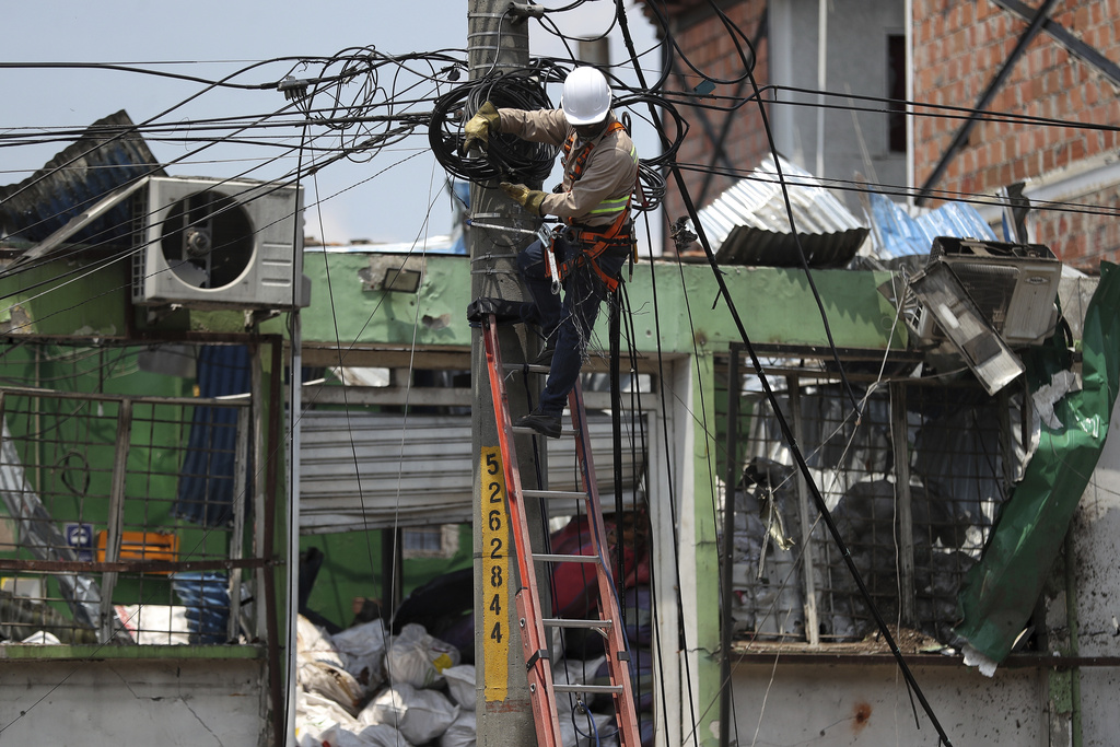 A power company worker fixes cables in the area damaged a day earlier by a car bomb explosion outside an Air Force base in Cali, Colombia, Friday, Aug. 22, 2025. (AP Photo/Santiago Saldarriaga)