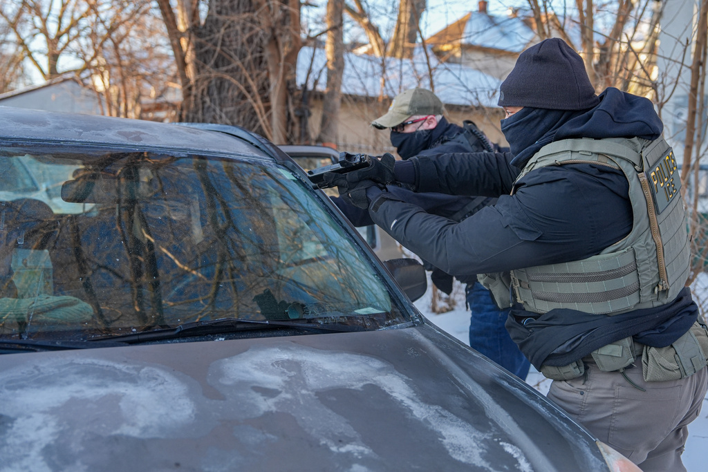 Activists are approached by a federal agent brandishing a firearm, for following agent vehicles, on Tuesday, Feb. 3, 2026, in Minneapolis. (AP Photo/Ryan Murphy)