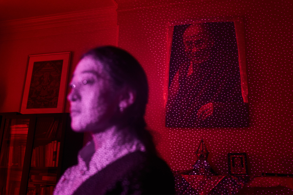 An image of the Dalai Lama and Namkyi, a Tibetan former political prisoner who was arrested and imprisoned at 15 for protesting Chinese rule, are illuminated by cellphone infrared facial recognition beams as Namkyi sits for a photo at the Office of Tibet, Oct. 7, 2025, in Washington. (AP Photo/David Goldman)