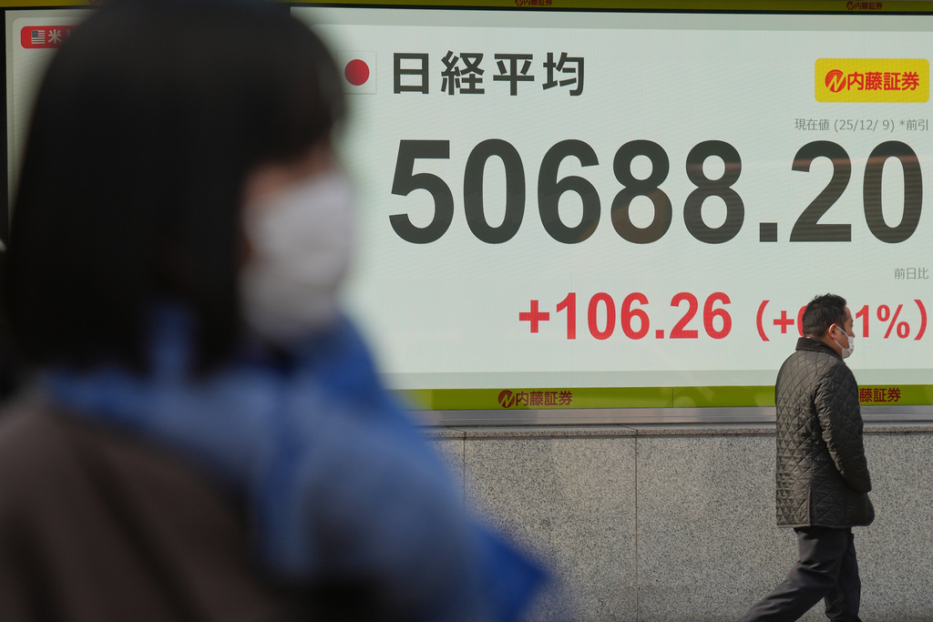A person walks in front of an electronic stock board showing Japan's Nikkei index at a securities firm Tuesday, Dec. 9, 2025, in Tokyo. (AP Photo/Eugene Hoshiko)