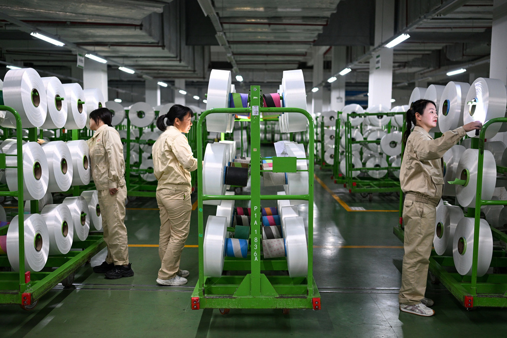 Workers check on the products in the world's largest production base for recycled polyester filament yarn, in Siyang, in east China's Jiangsu province on Oct. 24, 2025. (Chinatopix Via AP)
