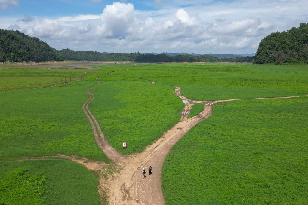 Researchers walk into the empty reservoir where Nithe Station, a depot on World War II's infamous "Death Railway" resurfaced after the reservoir was drained in Sangkhlaburi, Thailand on Friday, May 29, 2026. (AP Photo/Anton L. Delgado)