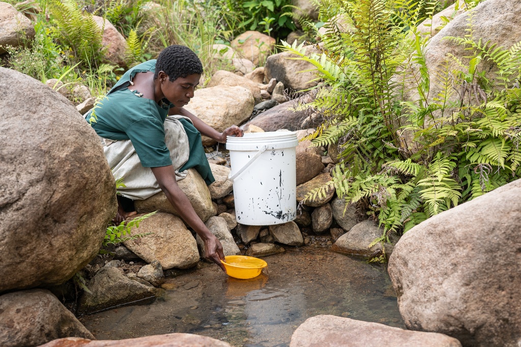 A woman draws water from a contaminated stream in Blantyre, southern Malawi, Thursday, Jan. 22, 2026. (AP Photo/Thoko Chikondi)