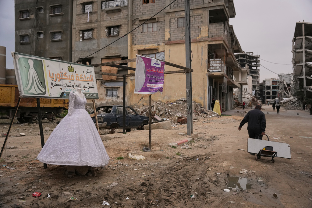 A Palestinian man walks past a wedding dress displayed on a street next to a bridal shop in Khan Younis, southern Gaza Strip, Thursday, Jan. 22, 2026. (AP Photo/Abdel Kareem Hana)