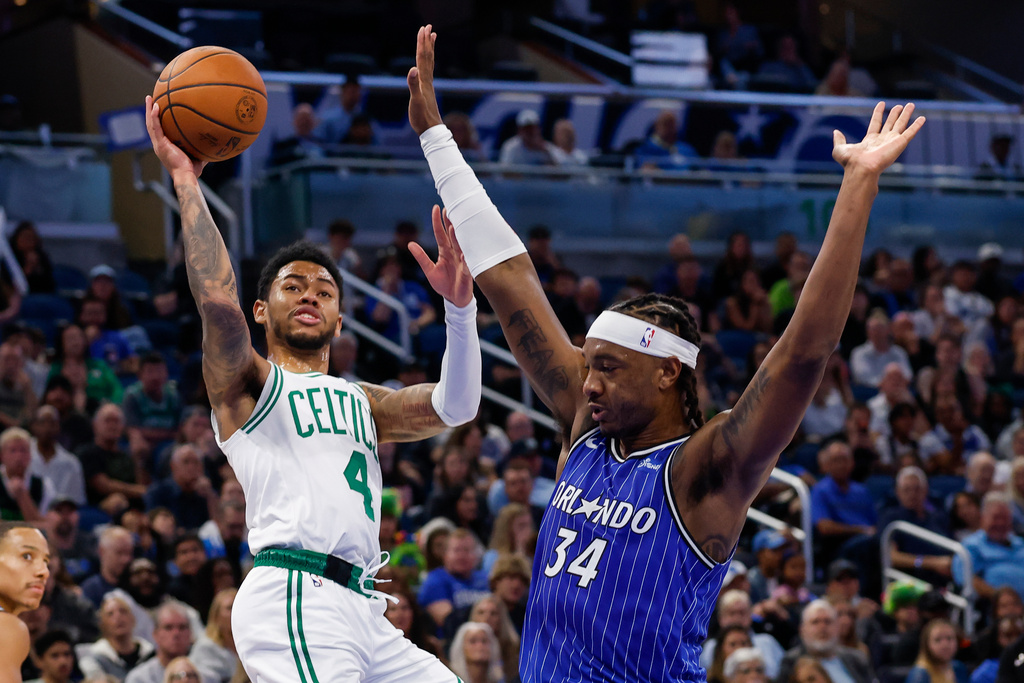 Boston Celtics guard Anfernee Simons (4) shoots two as he is fouled by Orlando Magic center Wendell Carter Jr. (34) during the first half of an NBA basketball game, Sunday, Nov. 9, 2025, in Orlando, Fla. (AP Photo/Kevin Kolczynski)