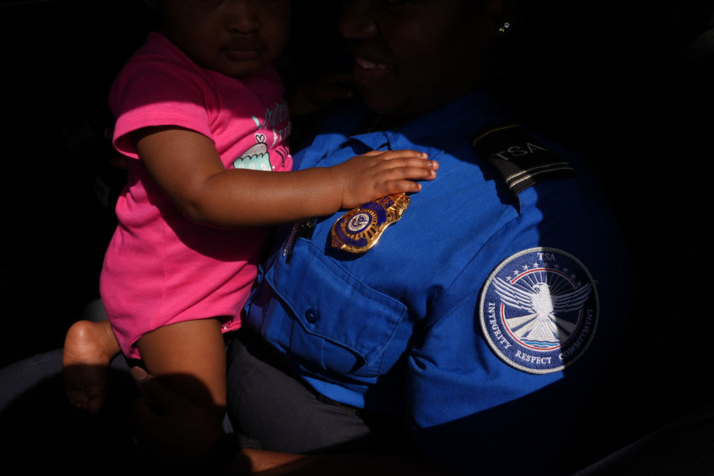 FILE - TSA agent Sashene McLean, holding her one-year-old daughter, comes from work to collect a donation of produce, meat and yogurt at a food distribution center organized to assist federal employees missing paychecks during the government shutdown in Dania Beach, Fla., Oct. 28, 2025. (AP Photo/Rebecca Blackwell, File)