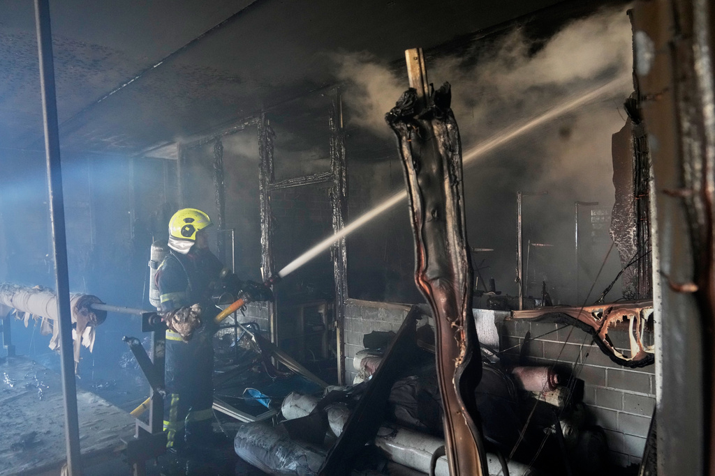 Firefighters put out the fire at a household services centre in a residential neighbourhood, following a Russia missile and drone attack, in Brovary, close to Kyiv, Ukraine, Saturday, March 14, 2026. (AP Photo/Efrem Lukatsky)