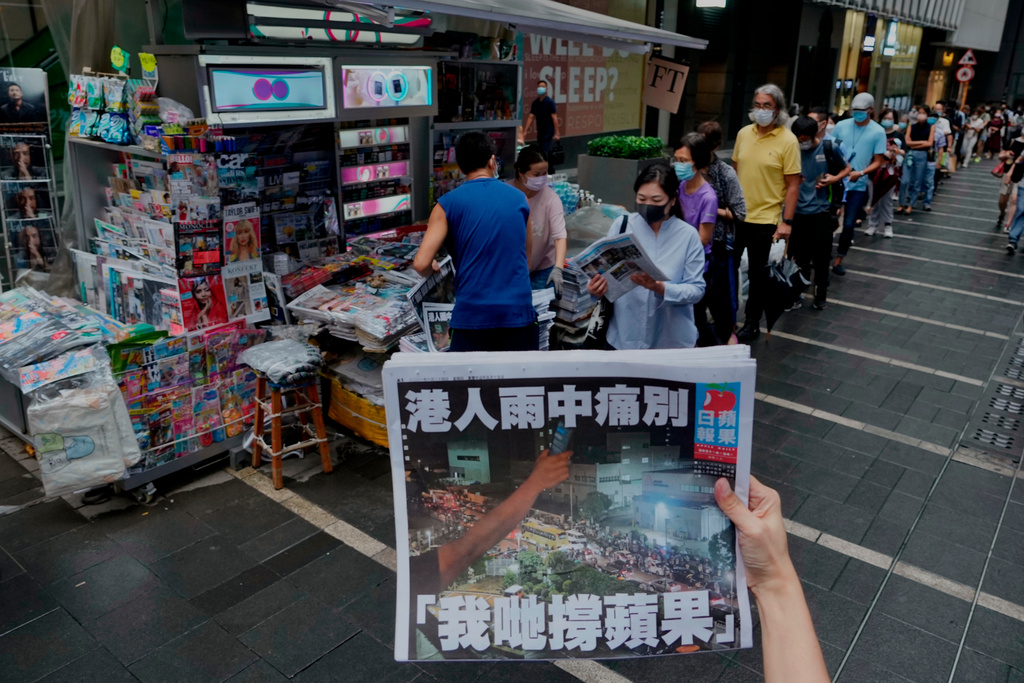 A woman takes a picture of the last issue of Apple Daily in front of a newspaper booth where people queue up to buy the newspaper in Hong Kong, June 24, 2021. (AP Photo/Vincent Yu, File)