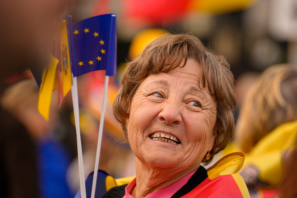 A woman smiles as she holds Moldovan and EU flags during a pro-EU rally of the ruling Party of Action and Solidarity (PAS), in Chisinau, Moldova, Friday, Sept. 26, 2025, ahead of parliamentary elections taking place on Sept.28. (AP Photo/Vadim Ghirda)