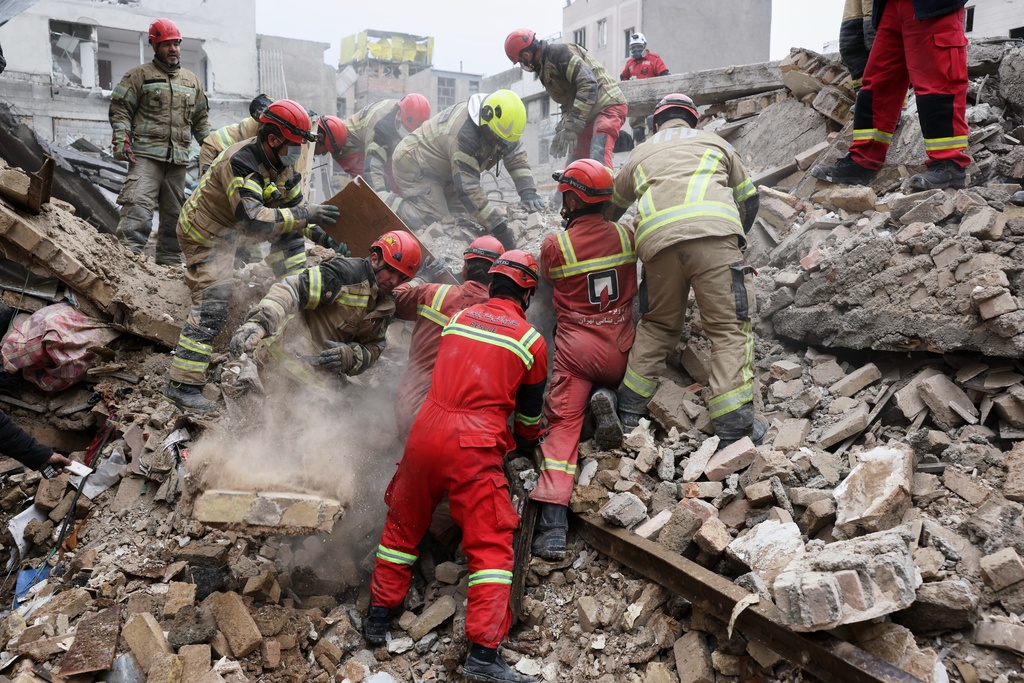 Rescue workers search for survivors in the rubble after a strike in southern Tehran, Iran, Friday, March 13, 2026. (AP Photo/Sajjad Safari)