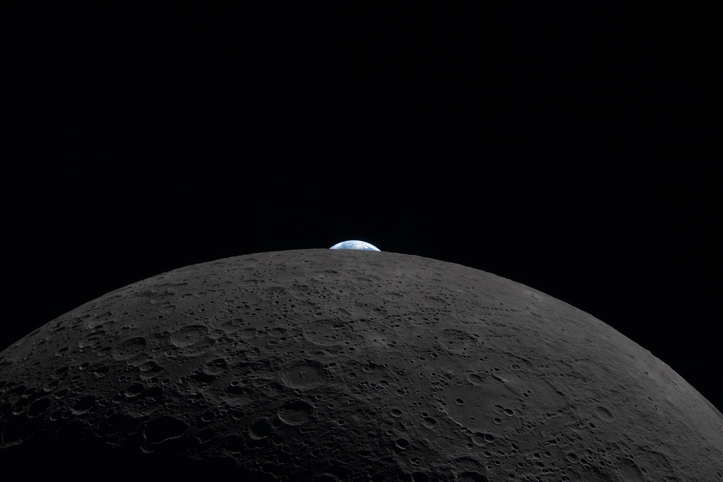 In this image provided by NASA, the Artemis II crew photographed the Earth peeking out over the horizon of the Moon on Monday, April 6, 2026. (NASA via AP)