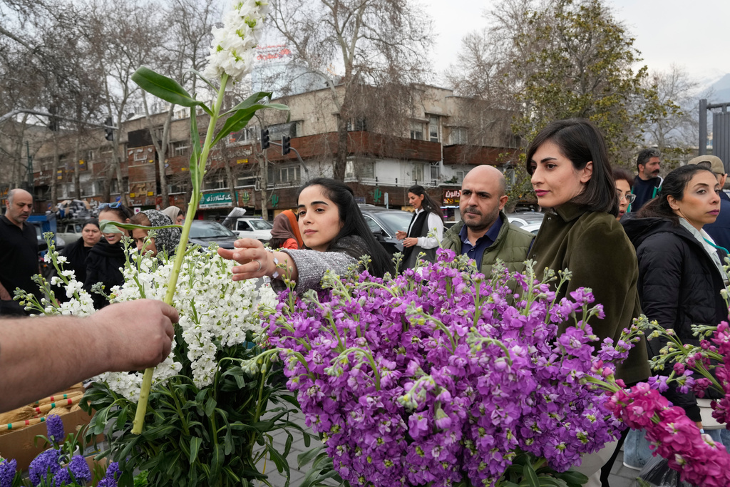 A woman shops for flowers ahead of the Persian New Year, or Nowruz, meaning "New Day," in northern Tehran, Iran, Thursday, March 19, 2026. (AP Photo/Vahid Salemi)