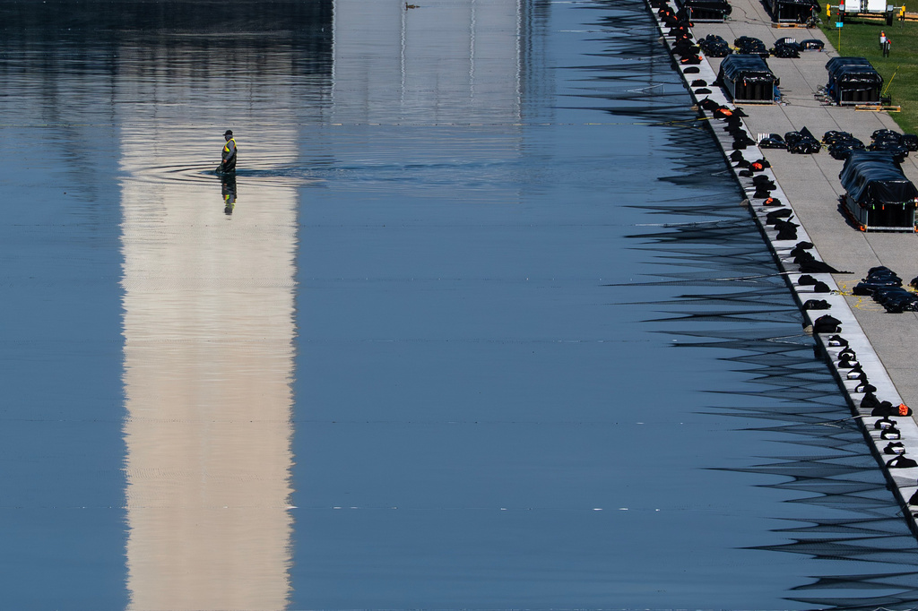 A worker wades through the Lincoln Memorial Reflecting Pool as crews install fireworks ahead of the America 250 July 4th celebration on the National Mall, Thursday, July 2, 2026, in Washington. (AP Photo/Nathan Howard)