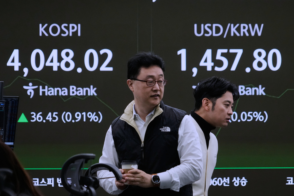 Currency traders pass by a screen showing the Korea Composite Stock Price Index (KOSPI), left, and the foreign exchange rate between U.S. dollar and South Korean won at the foreign exchange dealing room of the Hana Bank headquarters in Seoul, South Korea, Monday, Nov. 17, 2025. (AP Photo/Ahn Young-joon)