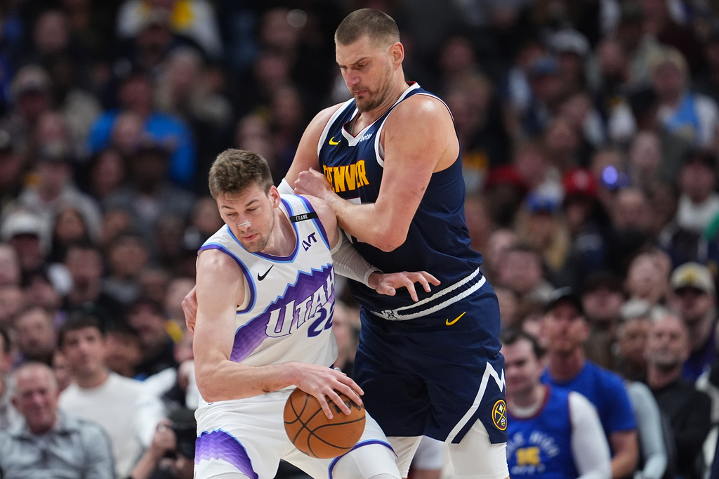Utah Jazz center Kyle Filipowski, left, collects a loose ball as Denver Nuggets center Nikola Jokić defends in the first half of an NBA basketball game Friday, March 27, 2026, in Denver. (AP Photo/David Zalubowski)