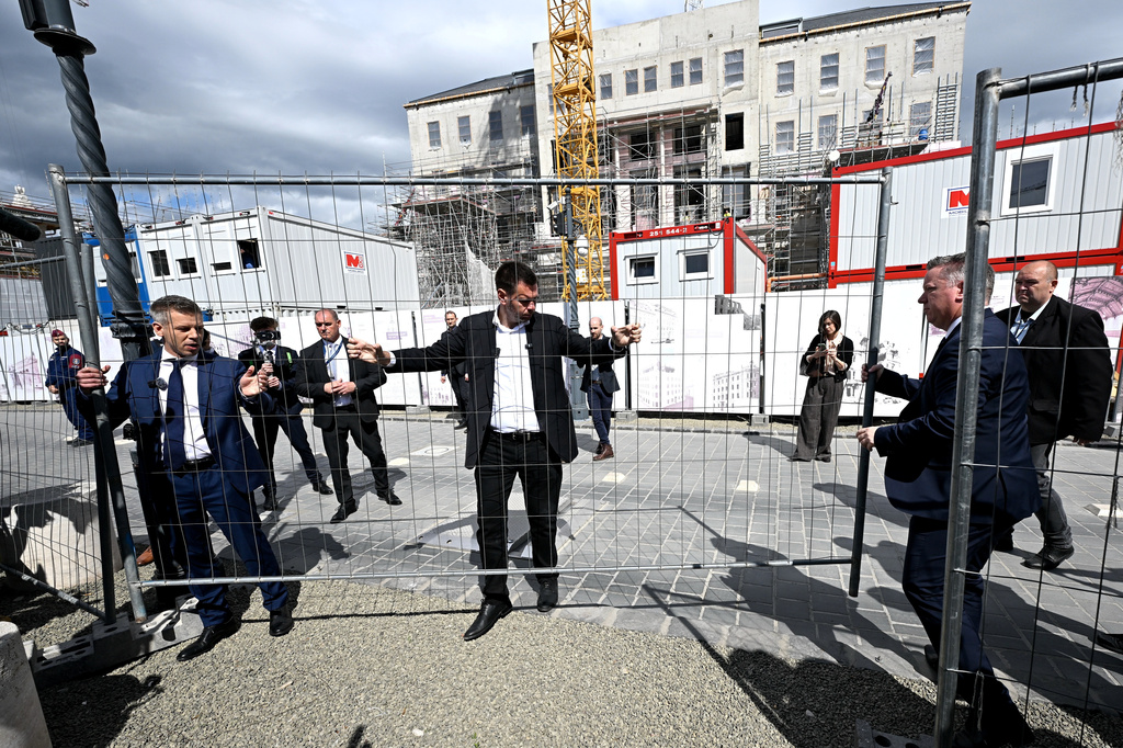 From left, Hungary's Prime Minister Peter Magyar, Minister of Transport and Innovation David Vitezy and Minister of Interior Gabor Posfai begin to dismantle the barricade surrounding the former Karmelita Palace, which has previously housed the Prime Minister's Office, in the Castle District of Budapest, Hungary, Friday, May 15, 2026. (Robert Hegedus/MTI via AP)