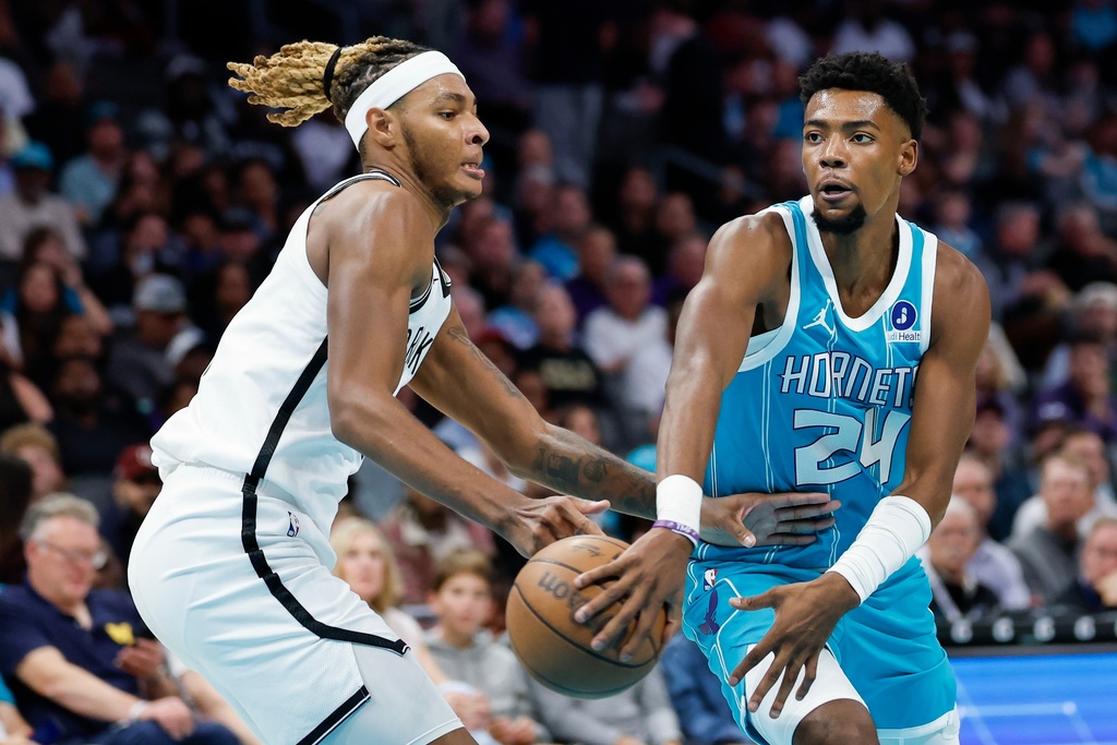 Charlotte Hornets forward Brandon Miller (24) passes around Brooklyn Nets forward Noah Clowney during the first half of an NBA basketball game in Charlotte, N.C., Wednesday, Oct. 22, 2025. (AP Photo/Nell Redmond)