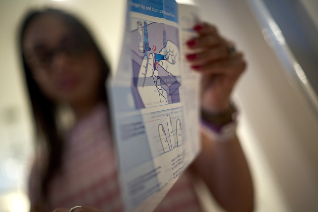 Ruth Wilson, who has lupus, unpacks a kit to prick her finger for a blood sample to share with her doctor whenever she experiences a flare up, Jan. 12, 2025, at her home in Littleton, Mass. (AP Photo/David Goldman)