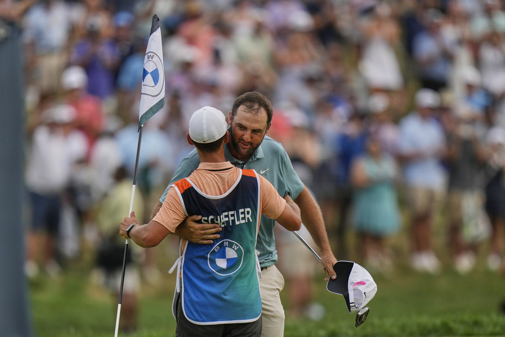 Scottie Scheffler, right, hugs his caddie Michael Cromie, left, on the 18th green after winning the BMW Championship golf tournament Sunday, Aug. 17, 2025, in Owings Mills, Md. (AP Photo/Stephanie Scarbrough)
