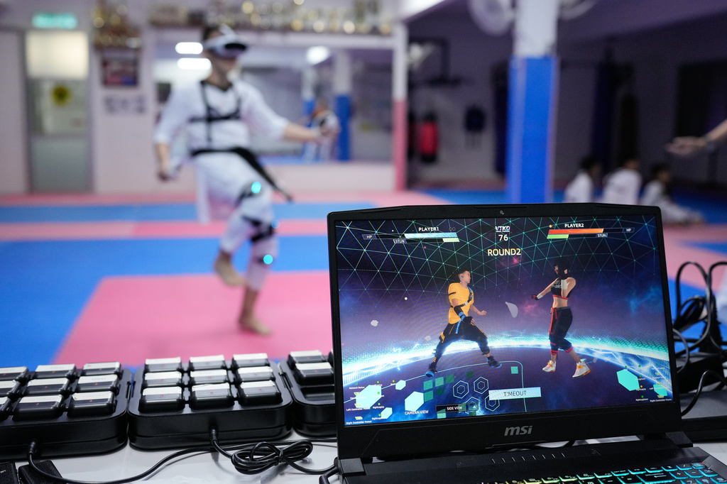 A laptop displays a virtual taekwondo match as a practitioner trains in Puchong, on the outskirts of Kuala Lumpur, Malaysia, Thursday, April 23, 2026. (AP Photo/Vincent Thian)