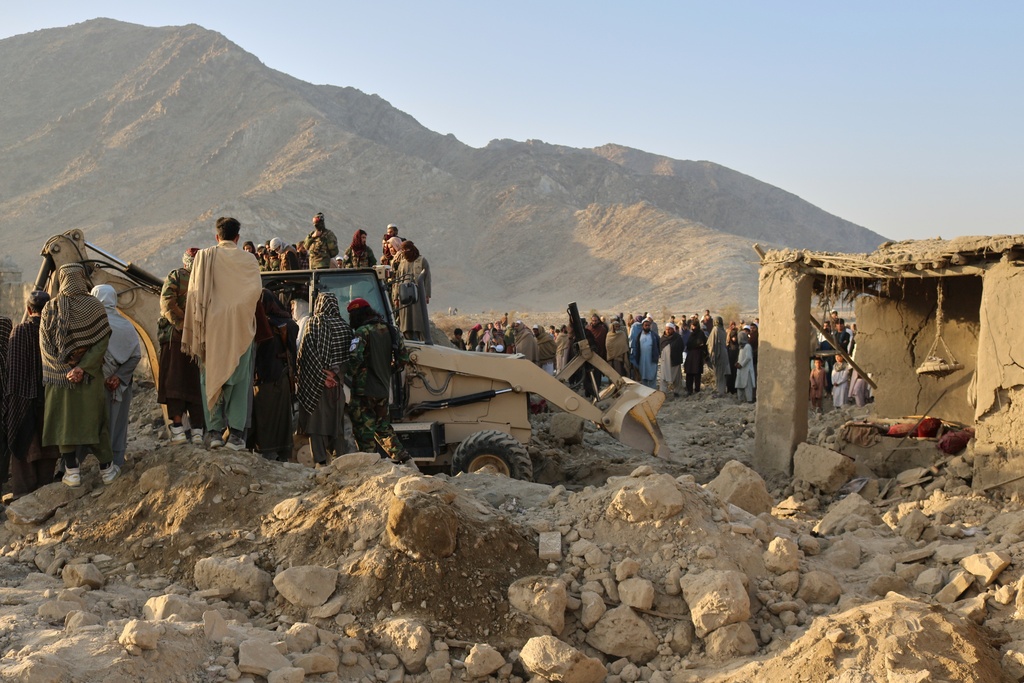 Local residents and civil defense workers look on as a bulldozer clears the rubble of a house hit by a cross-border Pakistani army strike in the Behsud district of Nangarhar province, Afghanistan, Sunday, Feb. 22, 2026. (AP Photo/Hedayat Shah)