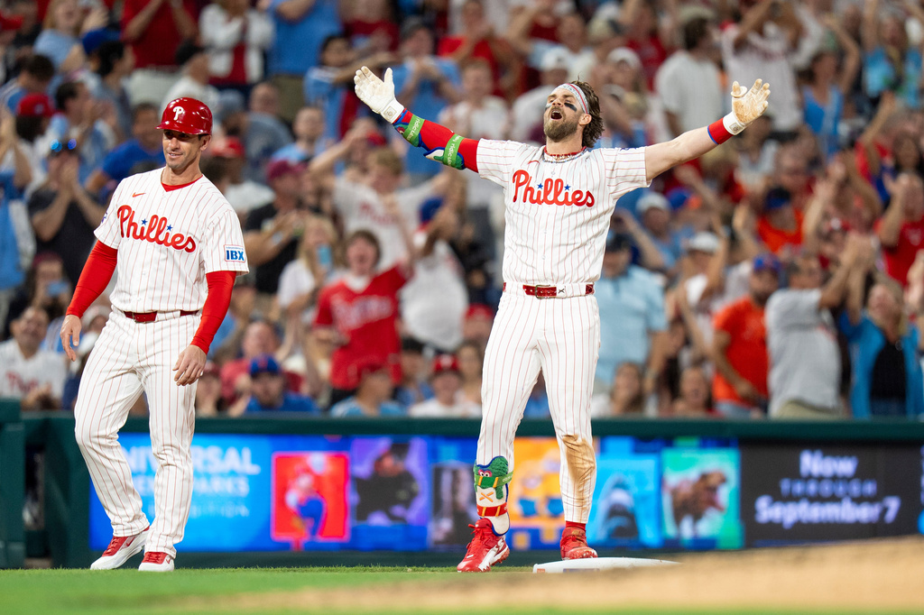 Philadelphia Phillies' Bryce Harper, right, reacts after his triple for the cycle during the fifth inning of a baseball game against the New York Mets, Saturday, June 20, 2026, in Philadelphia. (AP Photo/Chris Szagola)