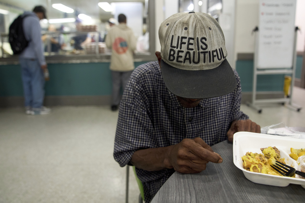 A guest of Miriam's Kitchen wears a hat saying, "Life is Beautiful," as he eats a meal, Wednesday, Aug. 13, 2025, at the organization which serves food to people who are homeless, in Washington. (AP Photo/Jacquelyn Martin)