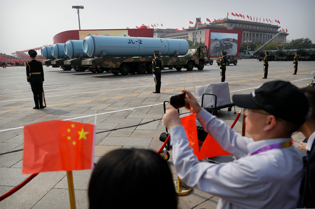 FILE - Spectators wave Chinese flags as military vehicles carrying JL-2 submarine-launched missiles roll during a parade to commemorate the 70th anniversary of the founding of Communist China in Beijing, Oct. 1, 2019. (AP Photo/Mark Schiefelbein, File)