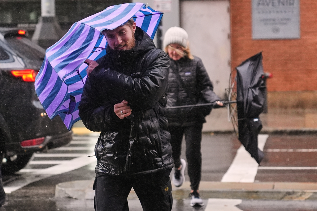 Two people battle gusts with their umbrellas as they fight a wind-driven rain storm, Monday, Oct. 13, 2025, in Boston. (AP Photo/Charles Krupa)