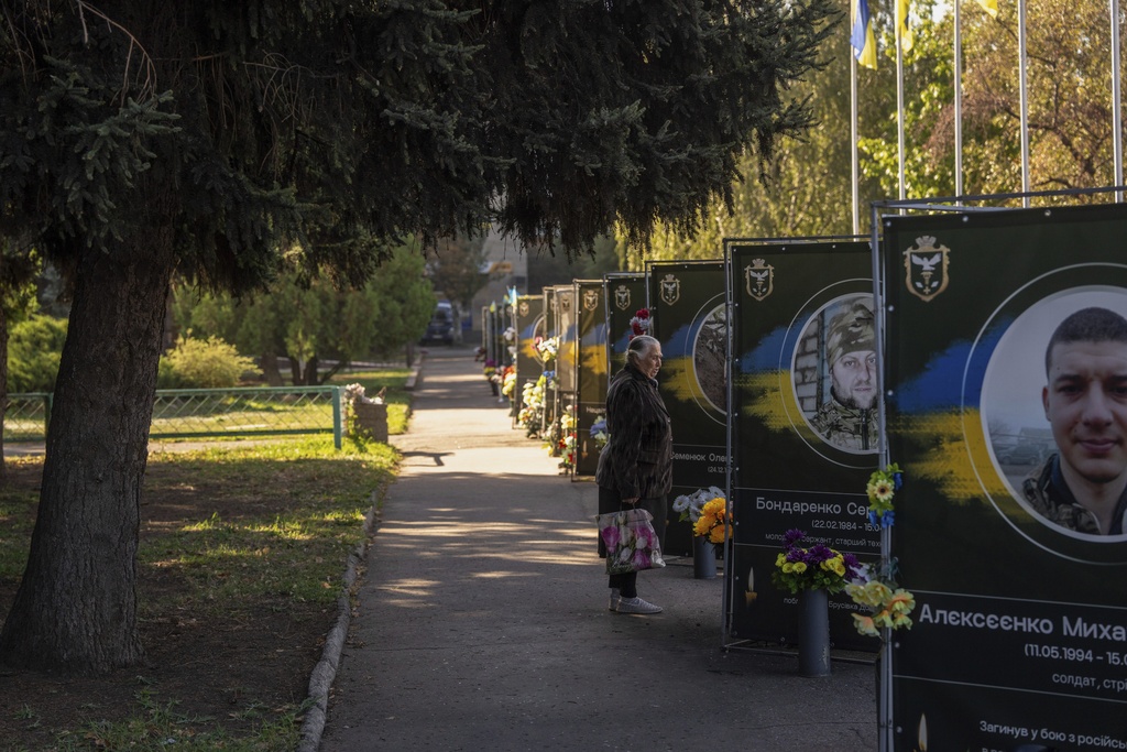 A woman cries while she looks at portraits of fallen servicemen in Sloviansk central square, Donetsk region, Ukraine, Friday, Sept. 12, 2025. (AP Photo/Alex Babenko)