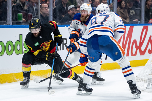 Vancouver Canucks' Conor Garland (8), Edmonton Oilers' Mattias Ekholm (14) and Connor McDavid (97) vie for the puck during third period NHL hockey action in Vancouver, British Columbia, Sunday, Oct. 26, 2025. (Ethan Cairns/The Canadian Press via AP) Vancouver Canucks' Conor Garland (8), Edmonton Oilers' Mattias Ekholm (14) and Connor McDavid (97) vie for the puck during third period NHL hockey action in Vancouver, British Columbia, Sunday, Oct. 26, 2025. (Ethan Cairns/The Canadian Press via AP)