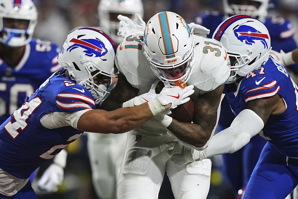 Miami Dolphins running back Ollie Gordon II (31) is tackled by Buffalo Bills safety Cole Bishop, left, and cornerback Christian Benford during the second half of an NFL football game, Thursday, Sept. 18, 2025, in Orchard Park, N.Y. (AP Photo/Matt Rourke)