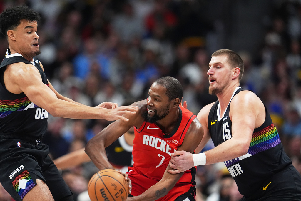 Houston Rockets forward Kevin Durant, center, look to pass the ball as Denver Nuggets forward Spencer Jones and center Nikola Jokić defend in the first half of an NBA basketball game Saturday, Dec. 20, 2025, in Denver. (AP Photo/David Zalubowski)