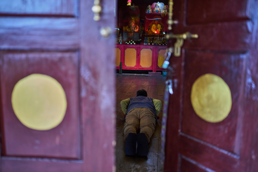 A Tibetan exile offers a prayer, seen through the door of a monastery, at a Tibetan refugee camp in Mustang, Saturday, April 19, 2025. (AP Photo/Niranjan Shrestha)