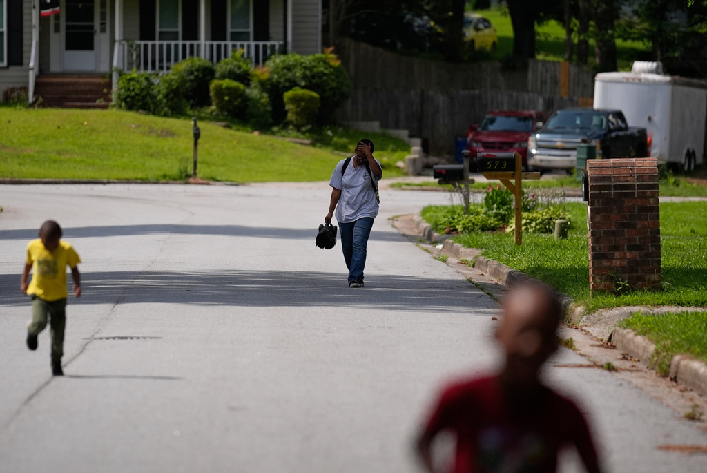 Sechita McNair, center, and sons Derrick McNair-White, right, and Malachi McNair-Nesbitt walk home through their neighborhood after a nearly two-hour public transportation trip from Atlanta to Jonesboro, Ga., on June 6, 2025. (AP Photo/Brynn Anderson)