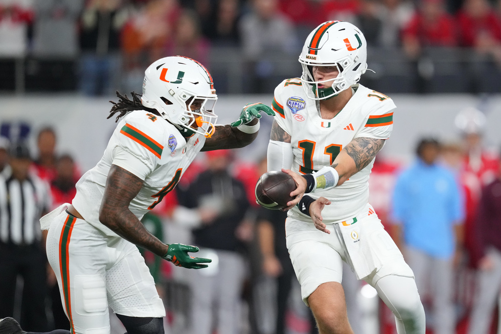 Miami quarterback Carson Beck, right, prepares to hand off to running back Mark Fletcher Jr. during the first half of the Cotton Bowl College Football Playoff quarterfinal game against Ohio State Wednesday, Dec. 31, 2025, in Arlington, Texas. (AP Photo/Julio Cortez)