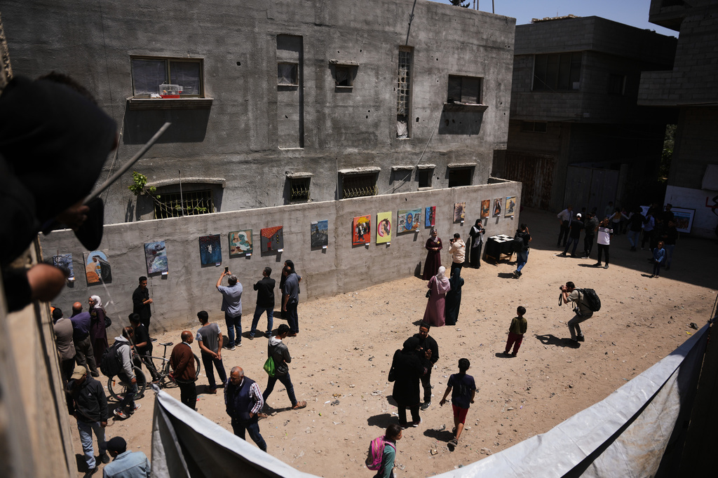 People look at paintings by Palestinian artists during an exhibition in Al-Bureij camp in the central Gaza Strip Tuesday, April 28, 2026. (AP Photo/Abdel Kareem Hana)
