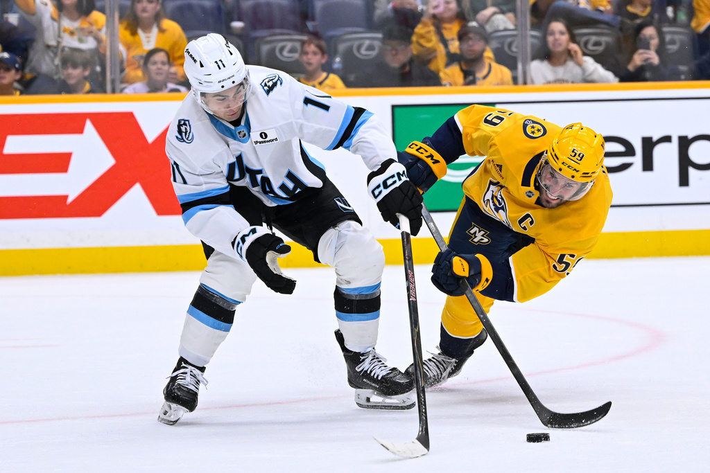 Utah Mammoth right wing Dylan Guenther (11) and Nashville Predators defenseman Roman Josi (59) vie for the puck during the second period of an NHL hockey game Saturday, Oct. 11, 2025, in Nashville, Tenn. (AP Photo/John Amis)