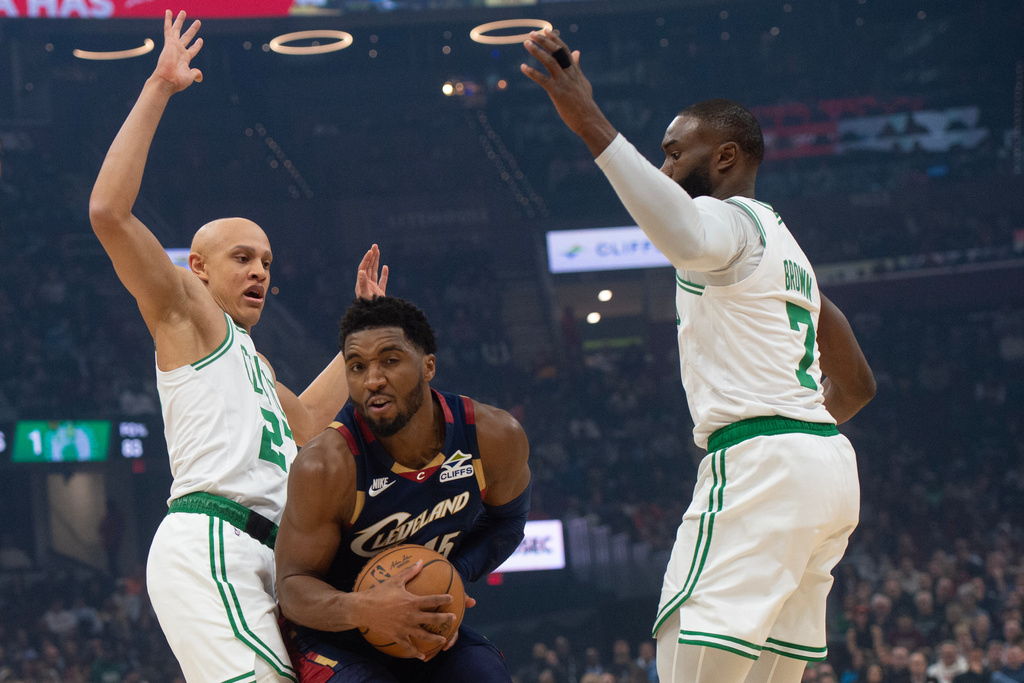 Cleveland Cavaliers' Donovan Mitchell, center, is guarded by Boston Celtics' Jordan Walsh, left, and Jaylen Brown during the first half of an NBA basketball game in Cleveland, Sunday, Nov. 30, 2025. (AP Photo/Phil Long)