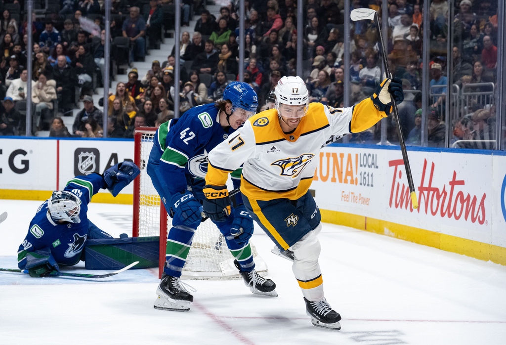 Nashville Predators' Tyson Jost (17) celebrates his goal as Vancouver Canucks' Curtis Douglas (42) watches and goaltender Nikita Tolopilo (60) looks to the net during the first period of an NHL game in Vancouver, on Thursday, March 12, 2026. (Ethan Cairns/The Canadian Press via AP)