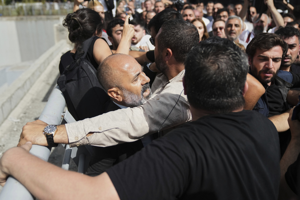 CORRECTS ID TO ERDEM UYGUR - Erdem Uygur, front left, a member of Turkey's main opposition Republican People's Party (CHP) is escorted by police officer as CHP supporters mob him outside the party's headquarters in Istanbul, Turkey, Monday, Sept. 8, 2025. (AP Photo/Francisco Seco)