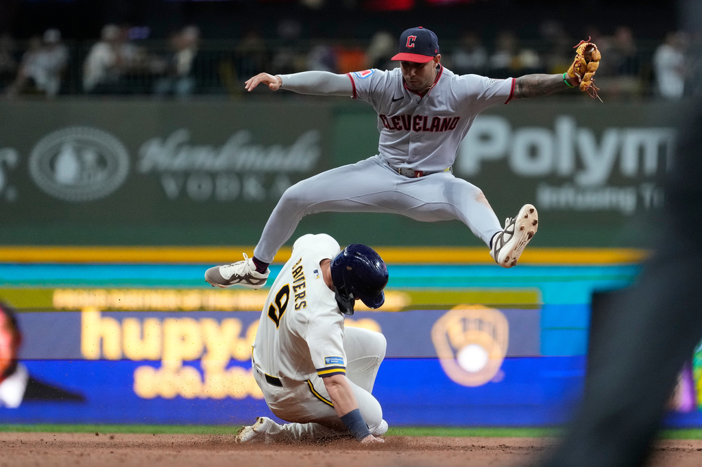 Cleveland Guardians' Brayan Rocchio leaps over Milwaukee Brewers' Jake Bauers after tagging him out at second base during the sixth inning of a baseball game, Tuesday, June 16, 2026, in Milwaukee. (AP Photo/Aaron Gash)