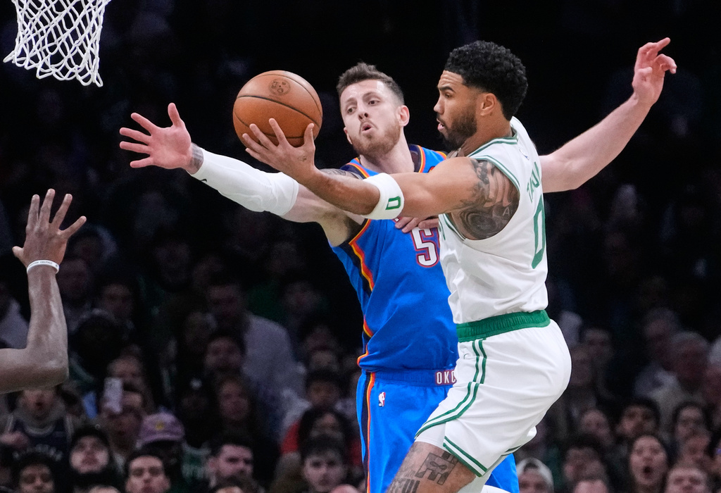 Boston Celtics forward Jayson Tatum, right, drives to the basket against Oklahoma City Thunder center Isaiah Hartenstein (55) during the first half of an NBA basketball game, Wednesday, March 25, 2026, in Boston. (AP Photo/Charles Krupa)
