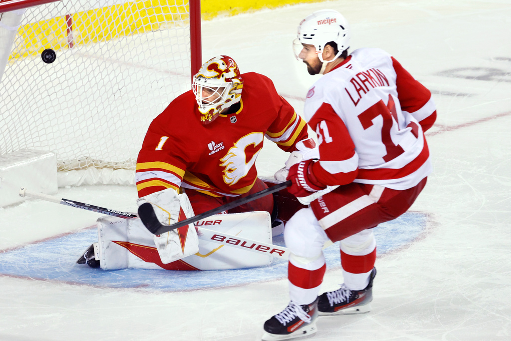 Detroit Red Wings' Dylan Larkin, right, scores on Calgary Flames goalie Devin Cooley during the second period of an NHL hockey game in Calgary, Alberta, on Wednesday, Dec. 10, 2025. (Larry MacDougal/The Canadian Press via AP)