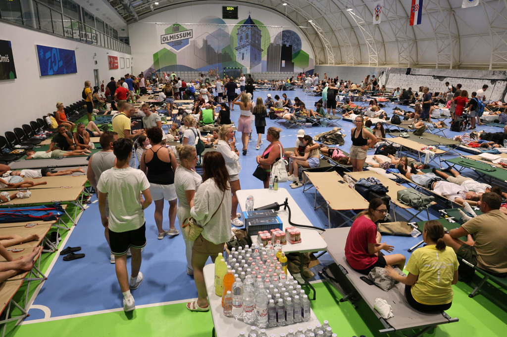 Residents and tourists evacuated from a wildfire gather inside a sports hall in Omis, southern Croatia early Friday, Aug. 14, 2026. (AP Photo/Jakov Prkic)