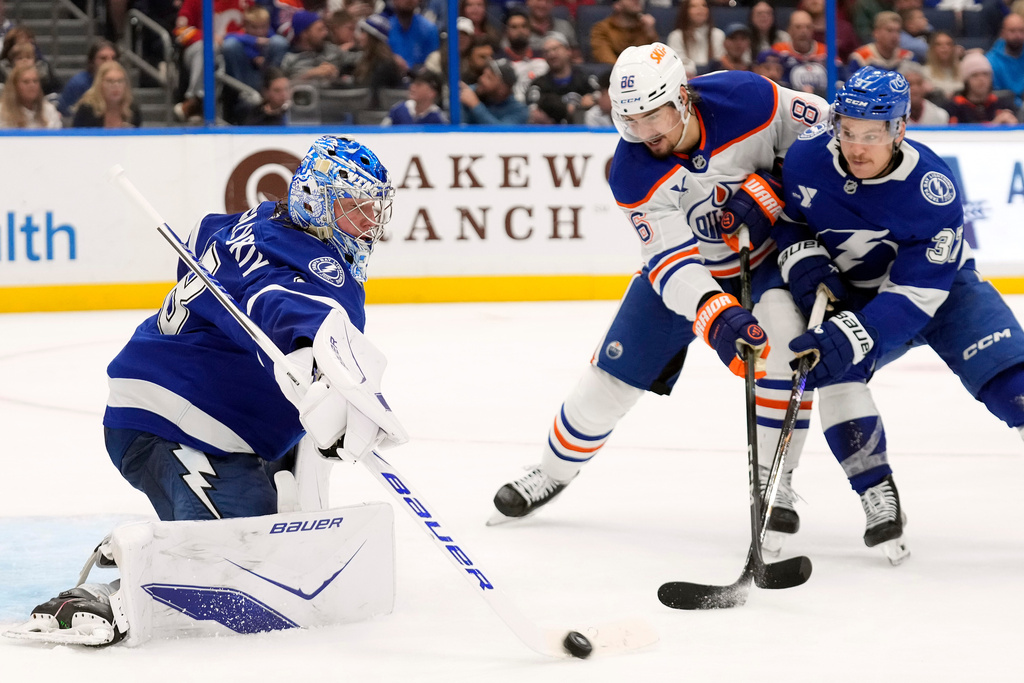 Tampa Bay Lightning goaltender Andrei Vasilevskiy (88) makes a stick save as center Yanni Gourde (37) keeps Edmonton Oilers right wing David Tomasek (86) from a rebound during the third period of an NHL hockey game Thursday, Nov. 20, 2025, in Tampa, Fla. (AP Photo/Chris O'Meara)