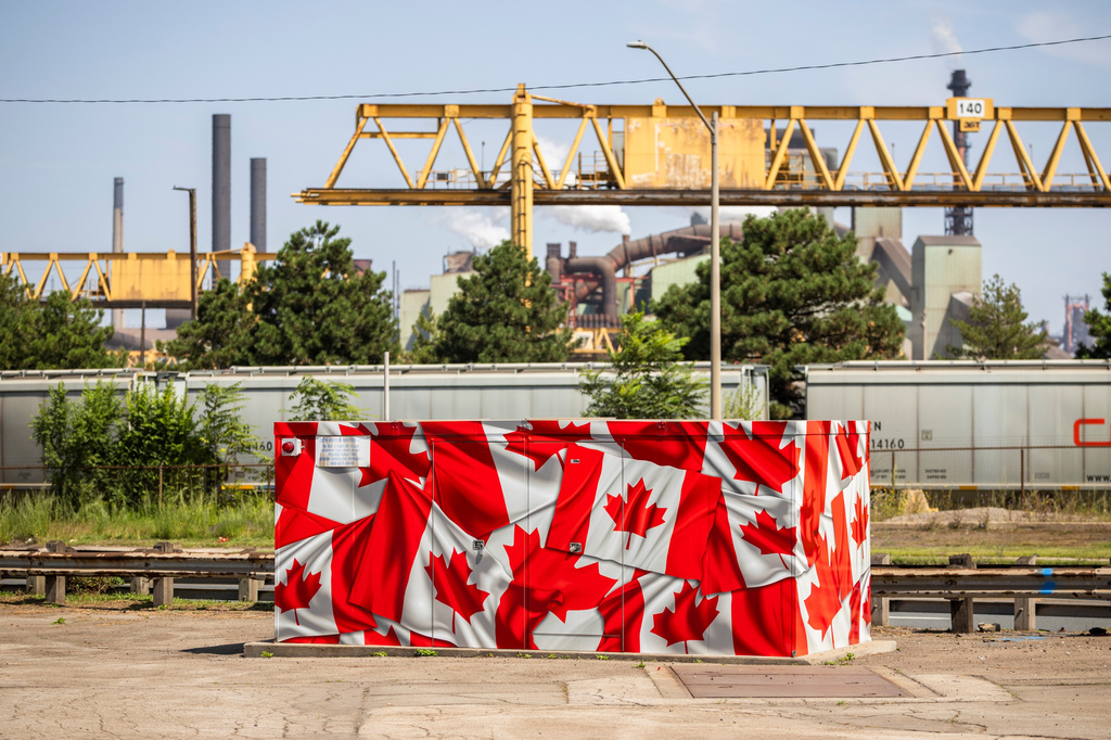 A utilities box covered in Canadian flags sits in front of the ArcelorMittal Dofasco steel plant in Hamilton, Ont. on Thursday, Aug. 20, 2026. (Nick Iwanyshyn /The Canadian Press via AP)
