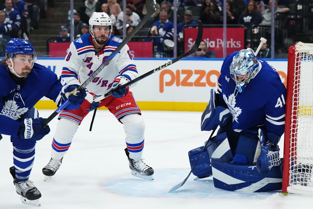 Toronto Maple Leafs goaltender Anthony Stolarz (41) makes a save against New York Rangers' J.T. Miller (8) as Maple Leafs' Simon Benoit (2) defends during first-period NHL hockey game action in Toronto, Thursday, Oct. 16, 2025. (Nathan Denette/The Canadian Press via AP)