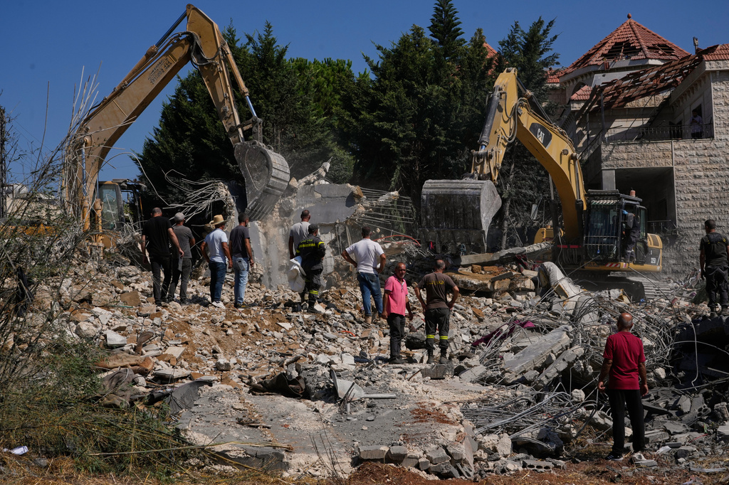 People watch rescue workers use excavators as they search for victims under the rubble of a building destroyed in an Israeli airstrike in the southern village of Kfar Rumman, Lebanon, Monday, Sept. 7, 2026. (AP Photo/Mohammed Zaatari)