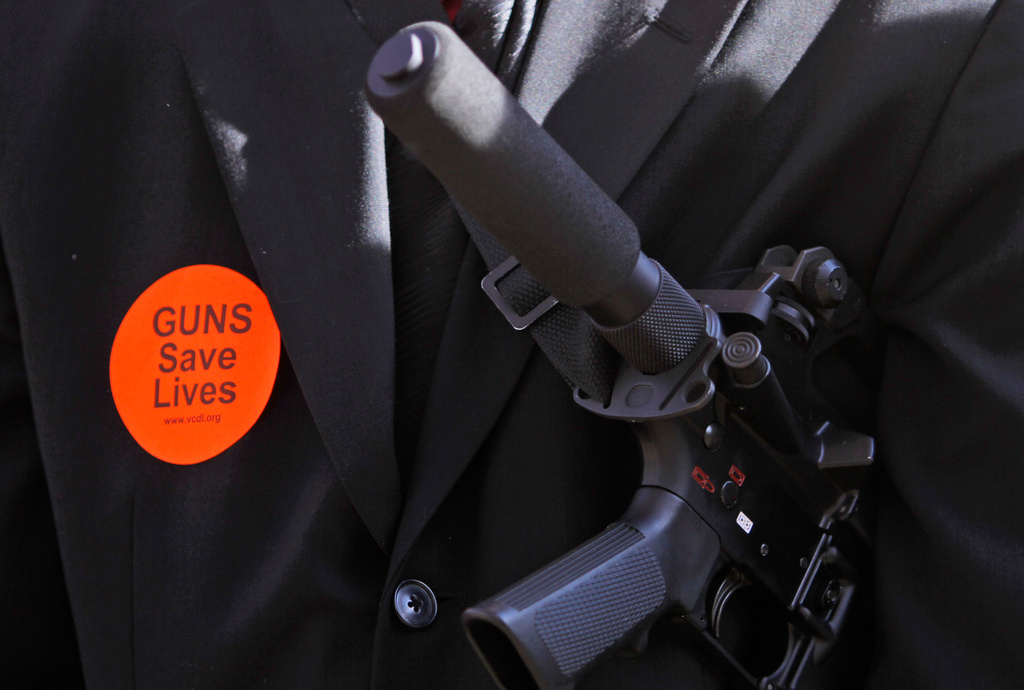 FILE - A demonstrator carries an AR-15 while wearing a "Guns Saves Lives" sticker during a gun rally at the Capitol in Richmond, Va., Jan. 16, 2012. (AP Photo/Steve Helber, File)